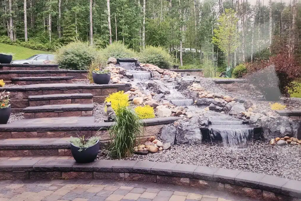pondless waterfall alongside steps and yellow shrubs
