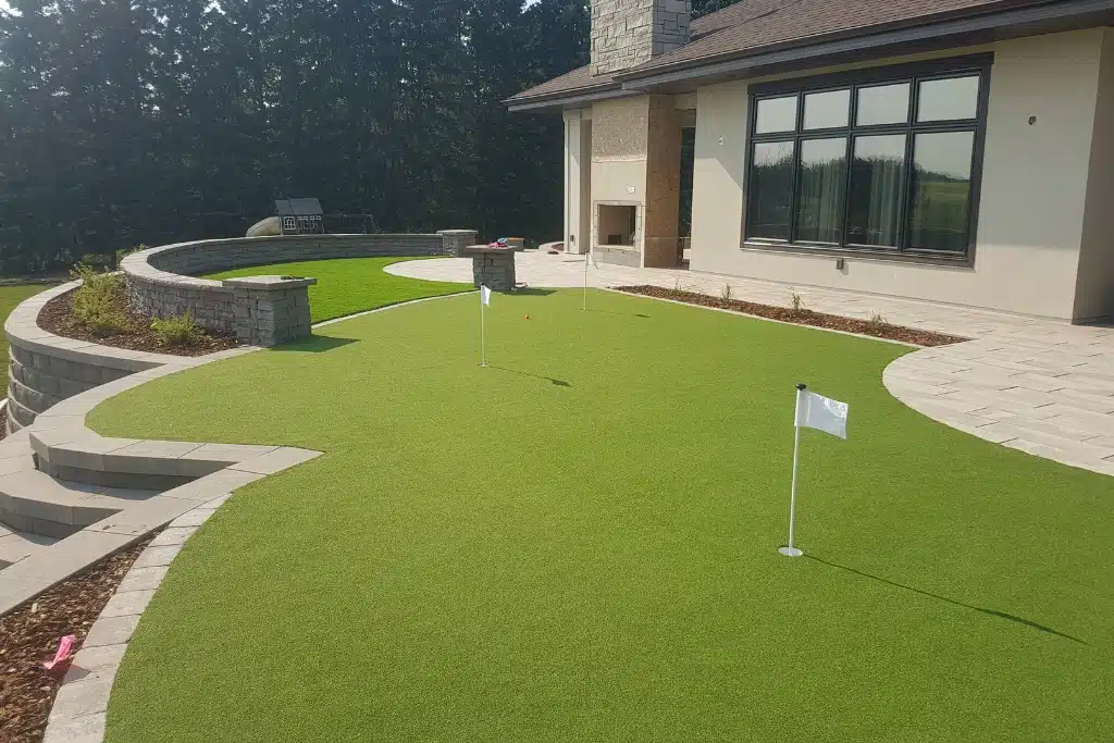Custom built putting green outside of a home, surrounded by patio and retaining walls