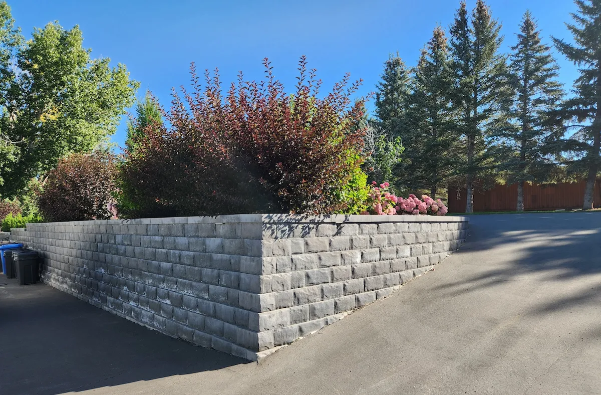 Keystone retaining wall along driveway with flourishing bushes and flowers